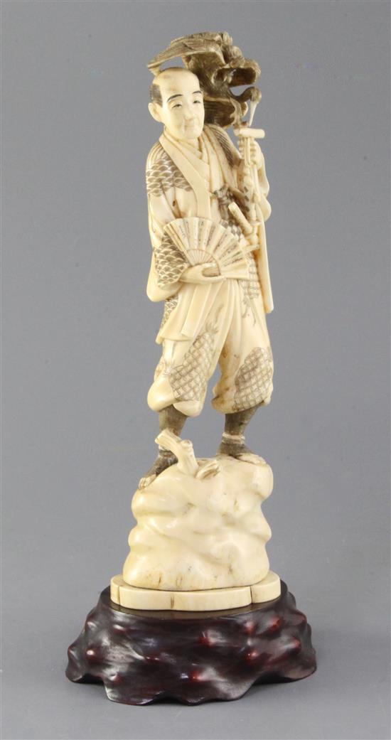 A Japanese walrus ivory okimono of a falconer, early 20th century, height including wood stand 33cm